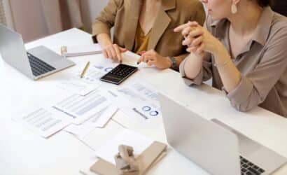 Accounting firm owner discussing client work at a desk in front of a laptop